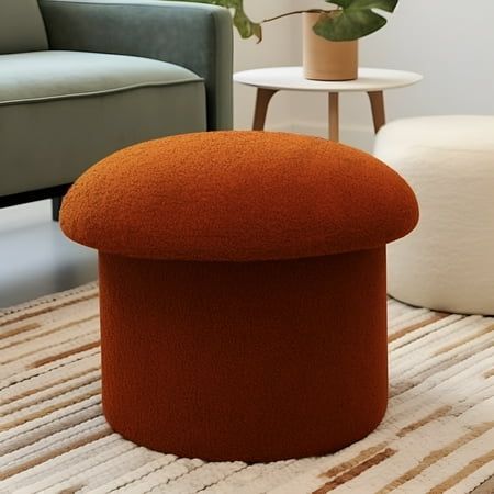 an orange ottoman sitting on top of a rug next to a chair and potted plant