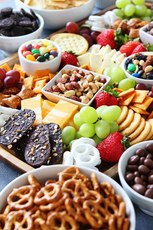 an assortment of snacks are arranged on a platter with grapes, strawberries, crackers and chocolates