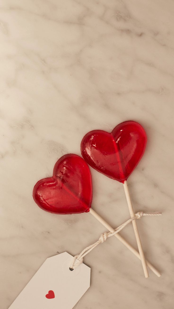 two heart shaped lollipops sitting on top of a white table next to a price tag