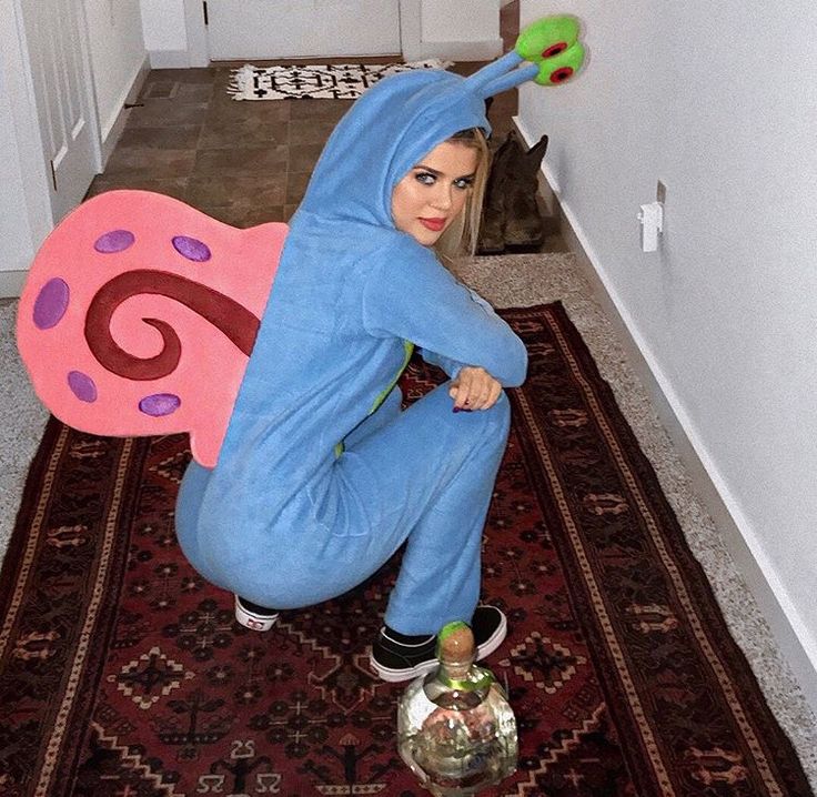 a woman in a blue costume with a pink butterfly on her back and green eyes