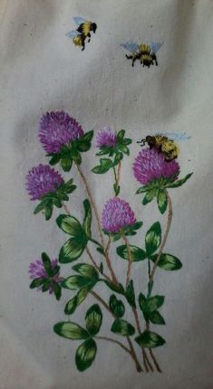 two bees flying over purple flowers on a white cloth with green leaves and pink flowers