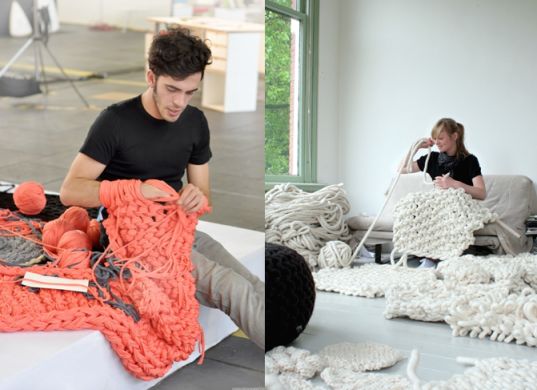 a man sitting on top of a couch next to a pile of knitted items