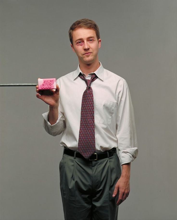 a man holding a pink object in one hand and a stick in the other with writing on it