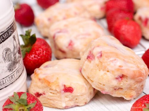 strawberry shortcakes with icing and strawberries next to a bottle of milk