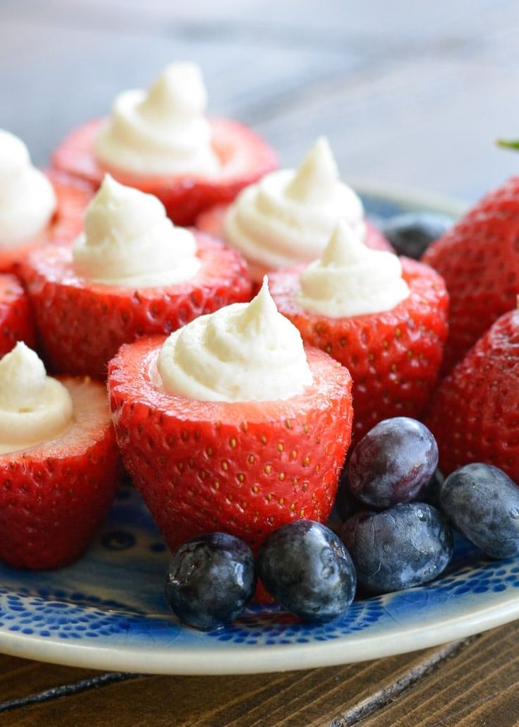 strawberries and blueberries are on a plate with cream cheese frosting in the middle