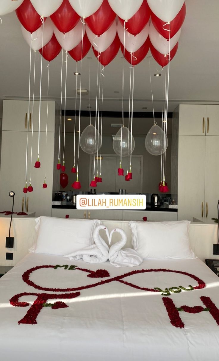 a bed with red and white balloons hanging from the ceiling