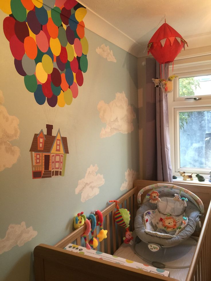 a baby's room with balloons hanging from the ceiling and toys on the crib