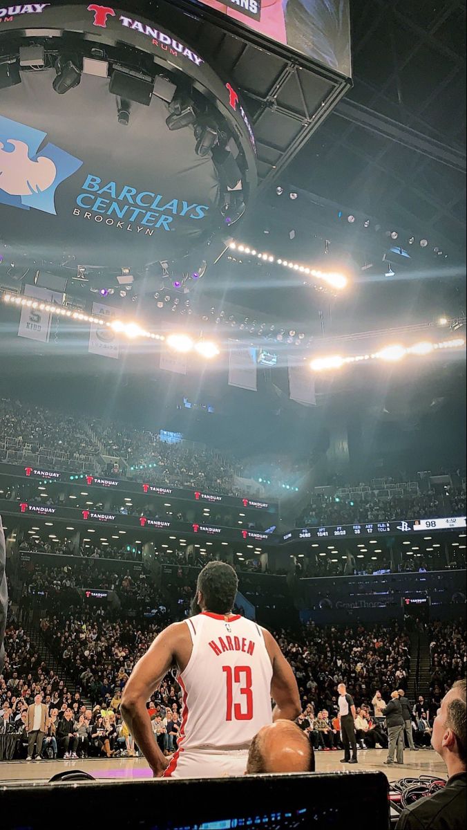 a basketball player is sitting in the middle of a large crowd at a sporting event