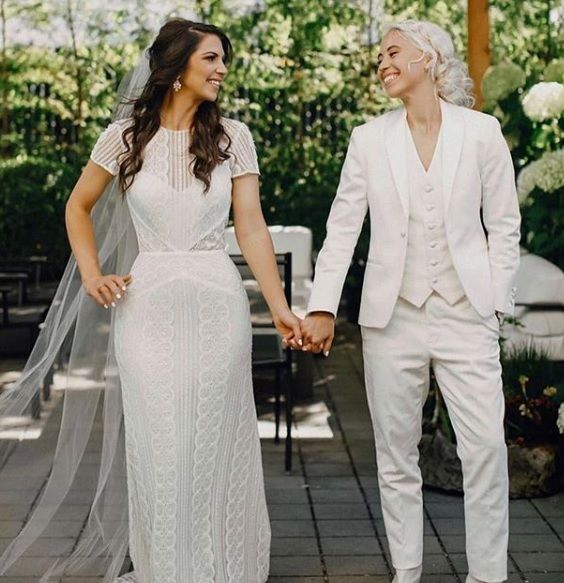 a bride and groom hold hands as they walk through an outdoor gazebo with greenery in the background