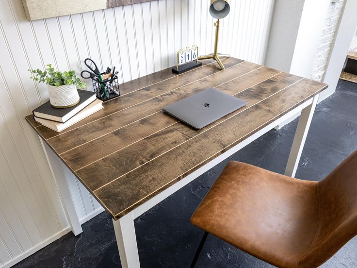 a wooden desk with a laptop on it and a brown leather chair next to it