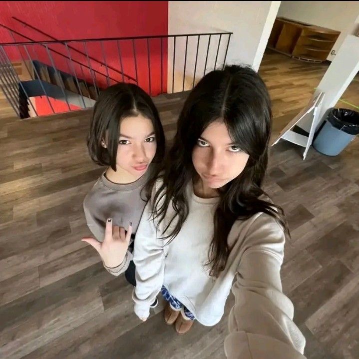 two young women standing next to each other on a wooden floor