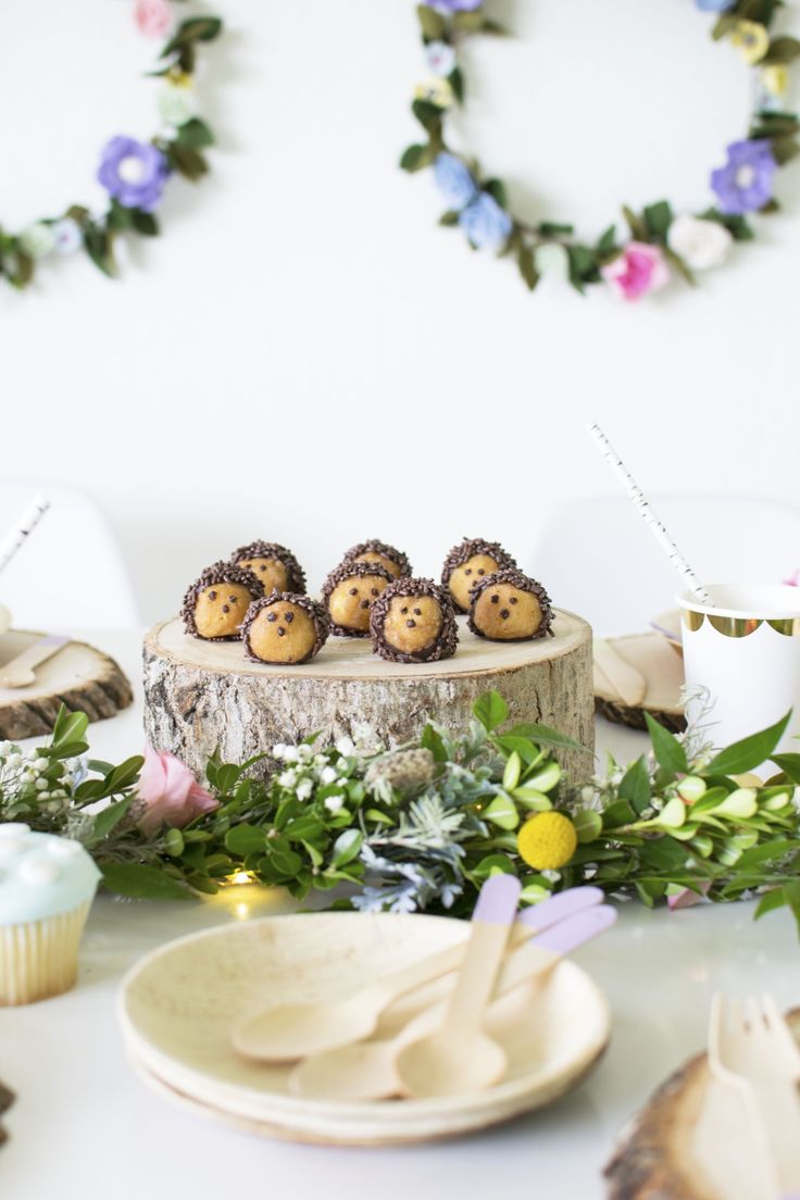 there are some cookies on top of a tree stump with flowers and candles in the background