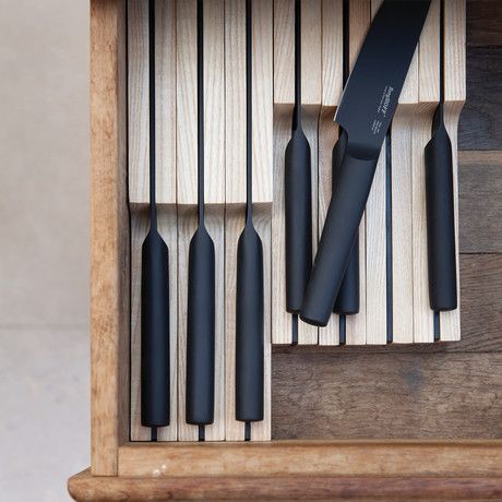 an assortment of black kitchen knives in a wooden box