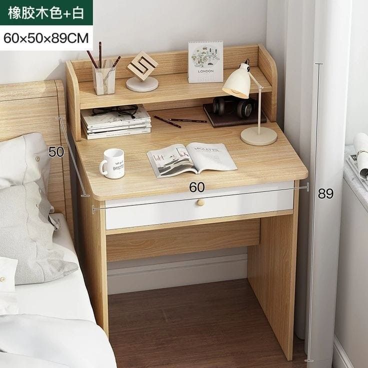 a small wooden desk with a lamp and books on it, next to a bed