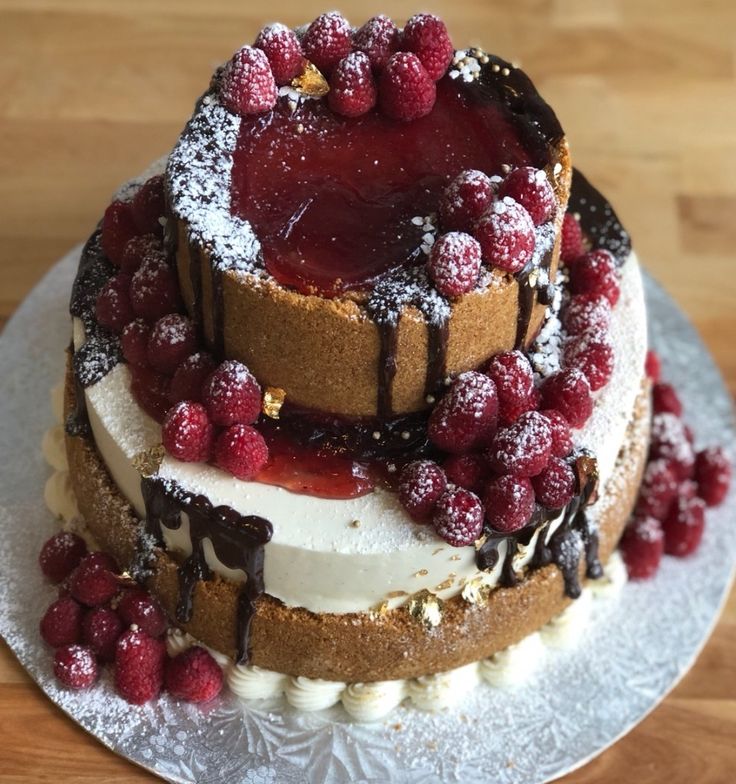 a three layer cake with raspberries on top