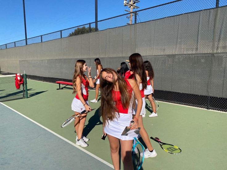 a group of young women standing on top of a tennis court