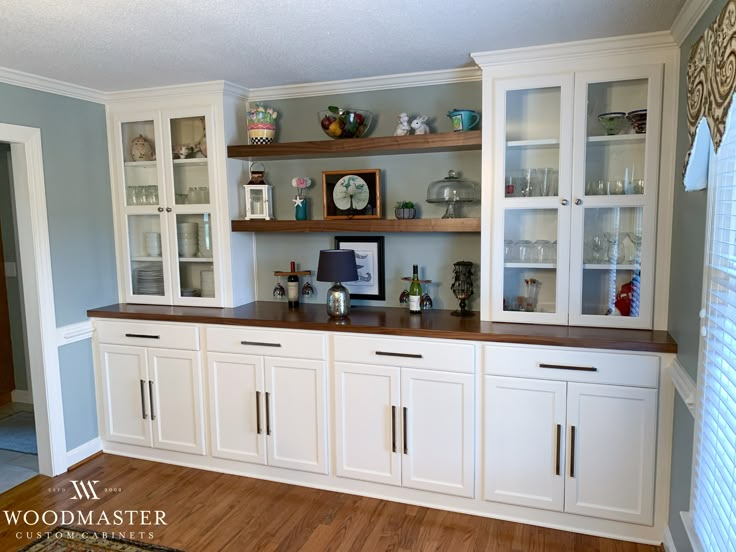 an empty kitchen with white cabinets and wood flooring in the center is seen here