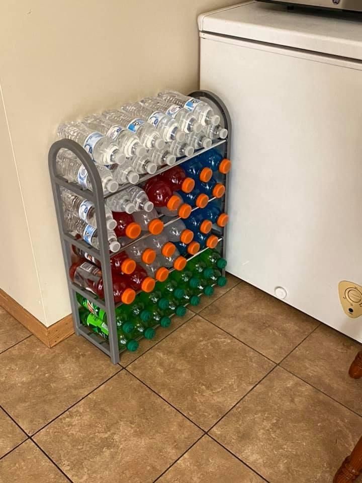 a stack of water bottles sitting on top of a floor next to a white refrigerator