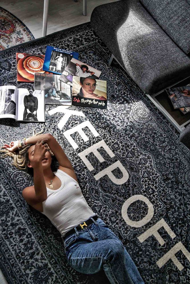 a woman laying on the floor with her head in her hands and magazines scattered around her