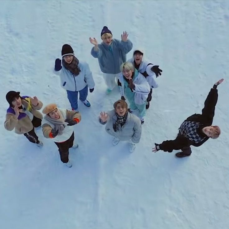 a group of people standing in the snow with their hands up and one person holding a teddy bear