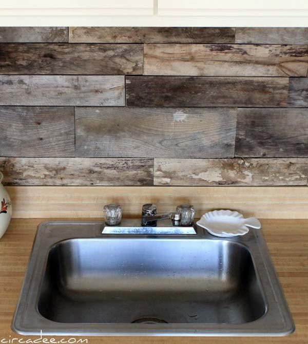 a kitchen sink with wooden wall behind it