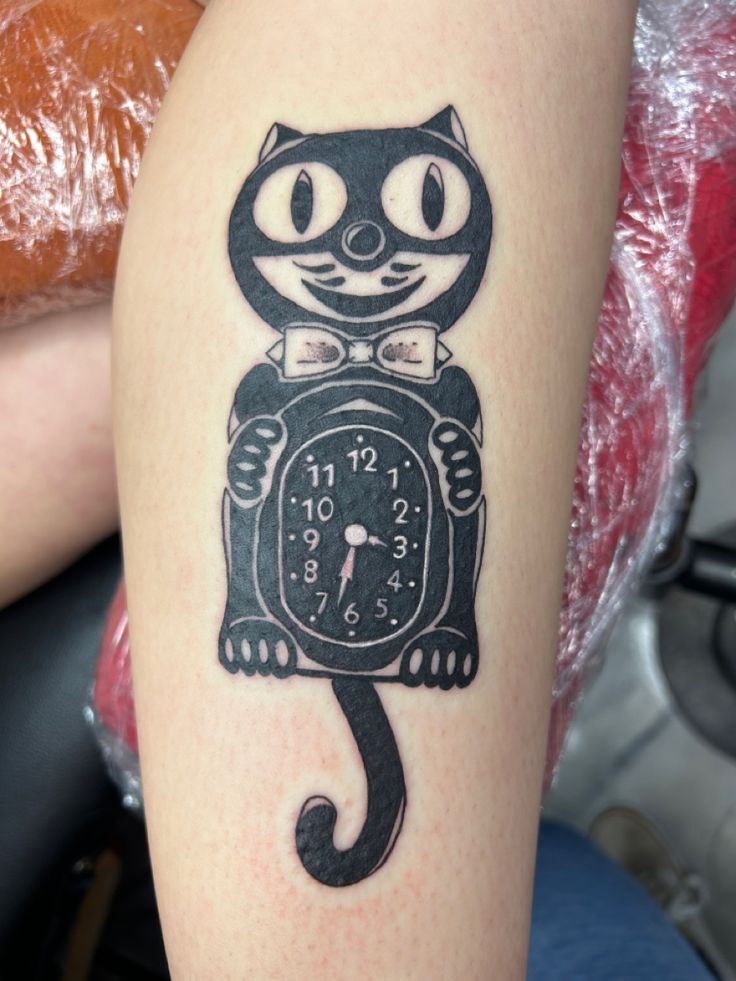 a black cat tattoo on the arm of a person with a clock in it's hand