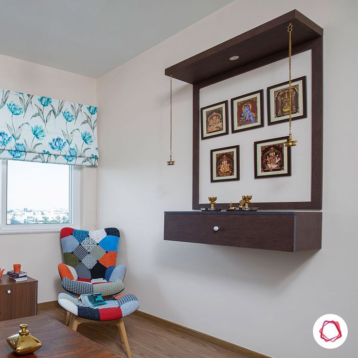 a living room with a chair, window and pictures on the wall above it's shelf