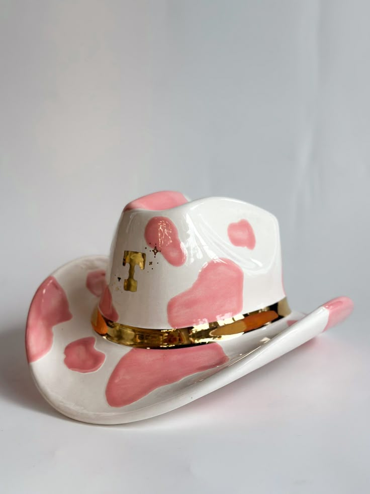 a white hat with pink hearts on it and a gold band around the brim