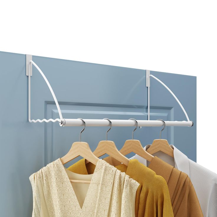 three shirts hanging on clothes racks in front of a blue wall and white door with an overhang