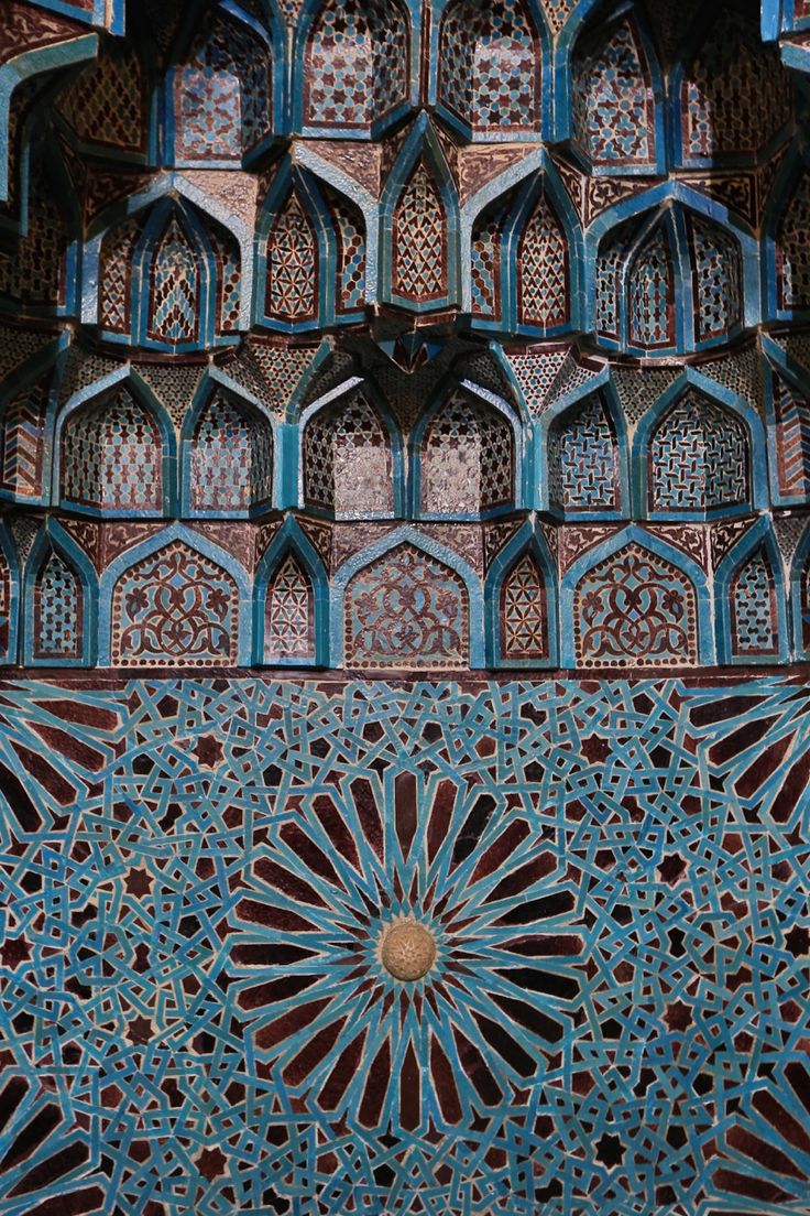 an intricately decorated wall in the middle of a building with blue and red tiles on it