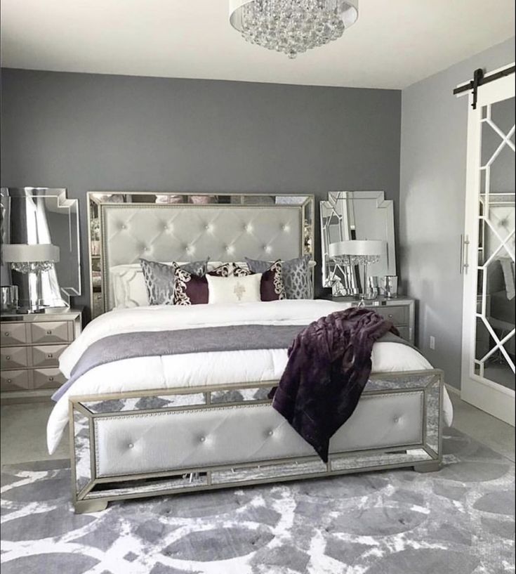 a bedroom with gray walls and white bedding, mirrored headboard and foot board