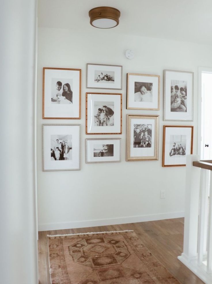 a wall with many pictures on it and a rug in front of the door way