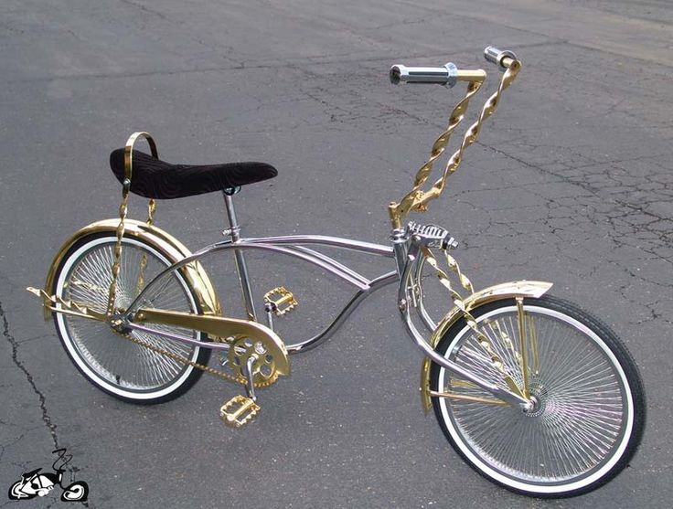 a gold and silver bicycle parked in a parking lot with a chain on the handlebars