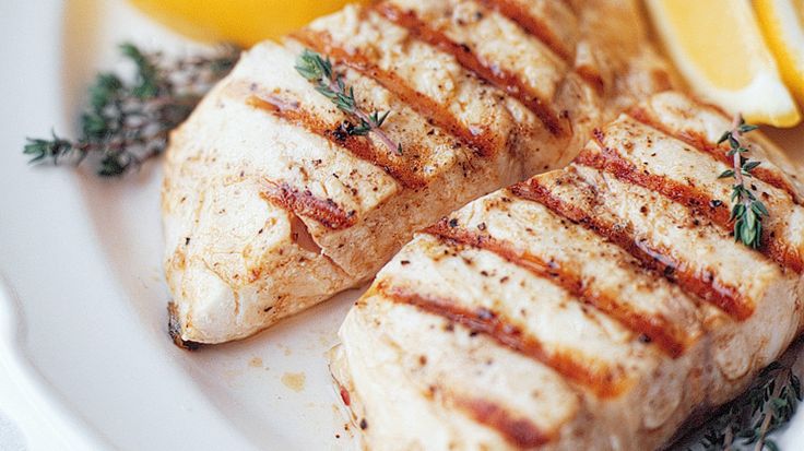 grilled fish with lemons and herbs on a white plate