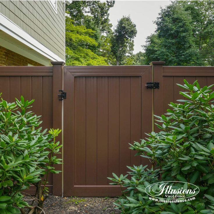 a brown fence with bushes and trees around it