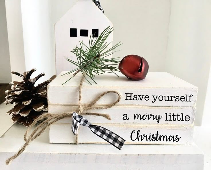 three books stacked on top of each other with christmas decorations and pine cones tied to them