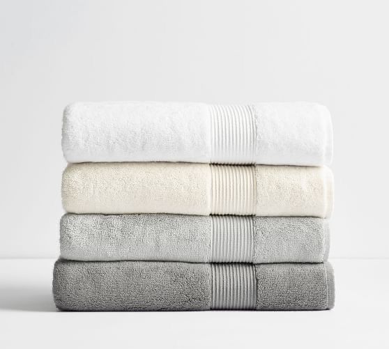 three towels stacked on top of each other in white and grey colors, with one folded