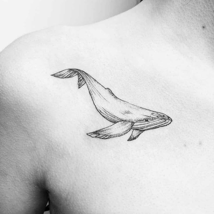 a black and white photo of a whale tattoo on the back of a man's chest