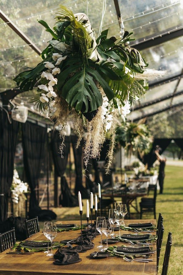 the table is set with place settings and flowers in vases, candles, and greenery