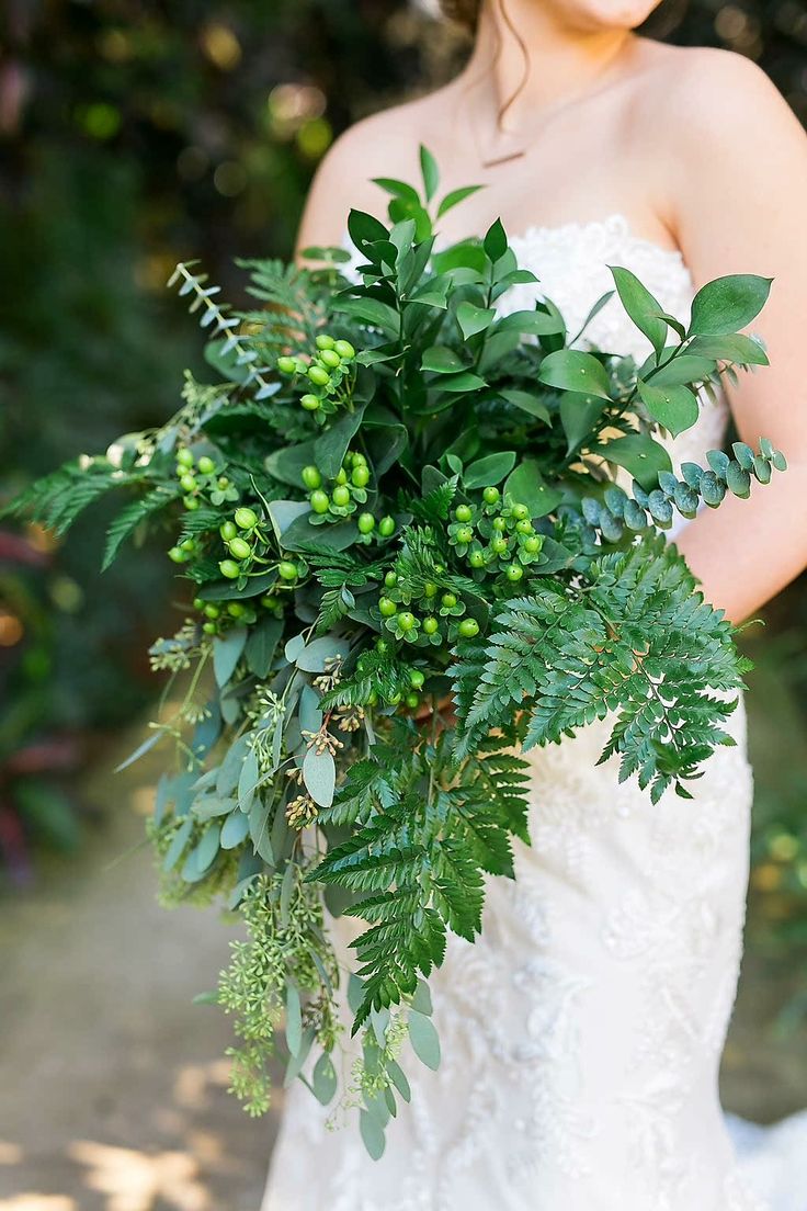 a bride holding a bouquet of greenery