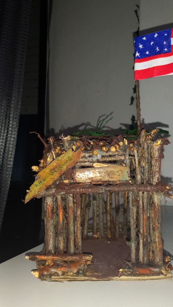 an american flag is on top of a small house made out of logs and branches