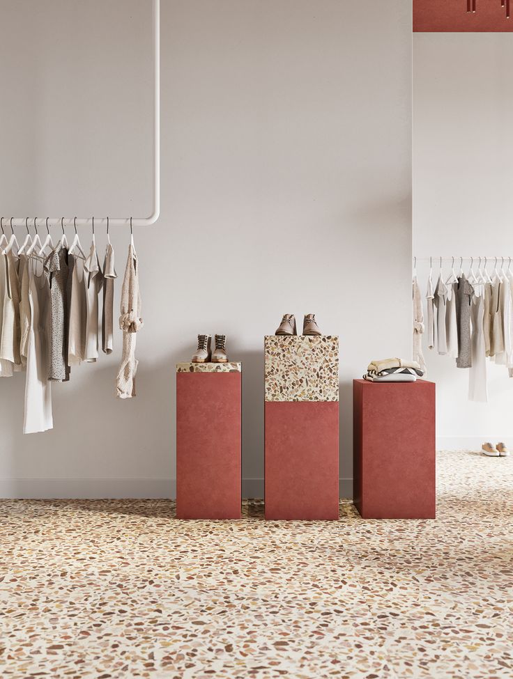 an empty room with clothes hanging on the rack and two boxes in front of them