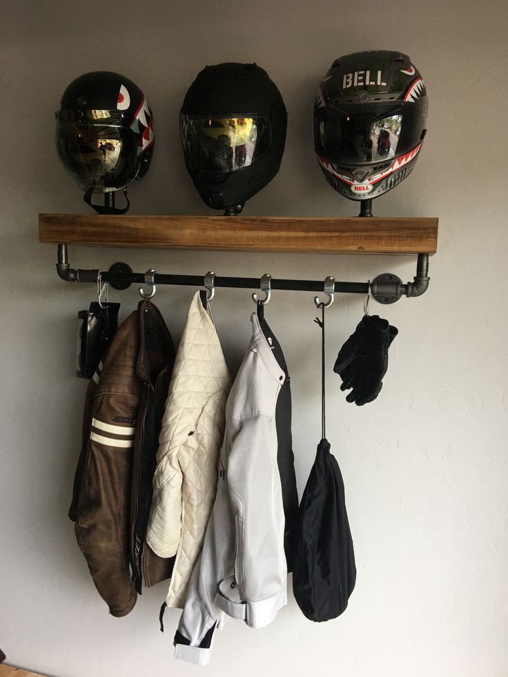 three helmets and gloves hanging on a wall next to a coat rack with two mitts