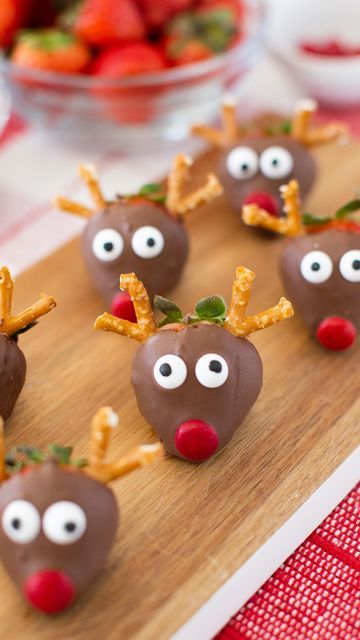 chocolate covered strawberries with reindeer noses on a cutting board and strawberries in the background