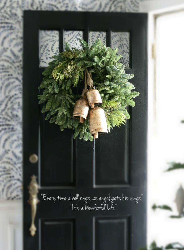 a black door with a wreath and bells on it