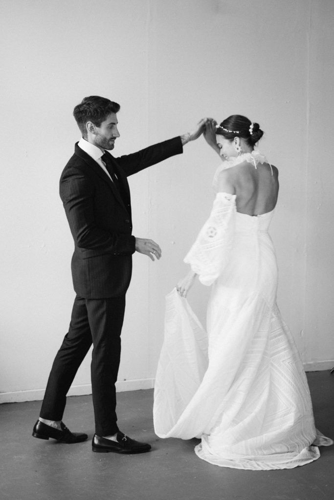 a man in a suit and tie adjusting the back of a woman's dress