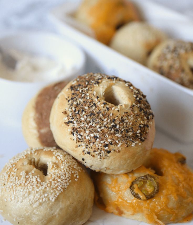 several bagels are stacked on top of each other with cheese and poppy seed sprinkles