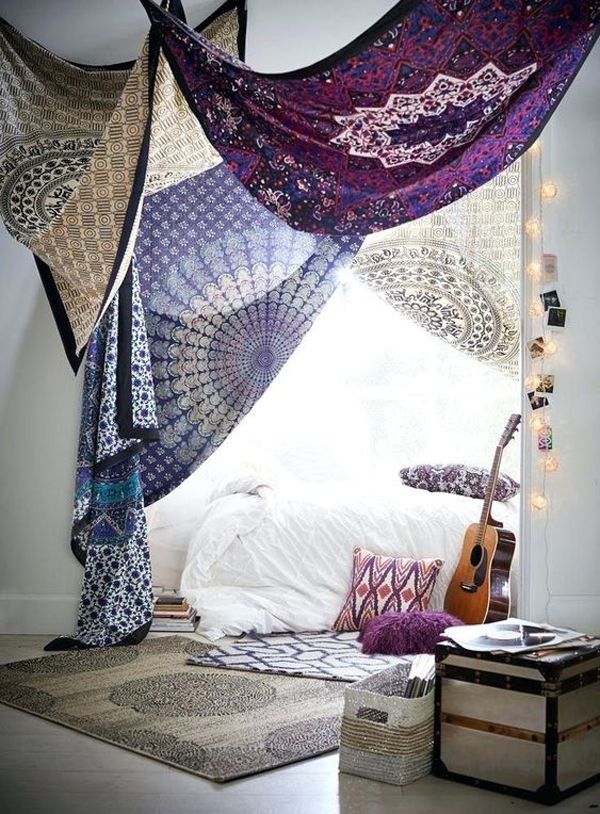 a bedroom with lots of colorful curtains hanging from the ceiling