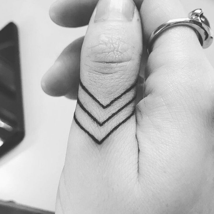 a woman's hand with a small tattoo on the middle finger and an arrow in the middle