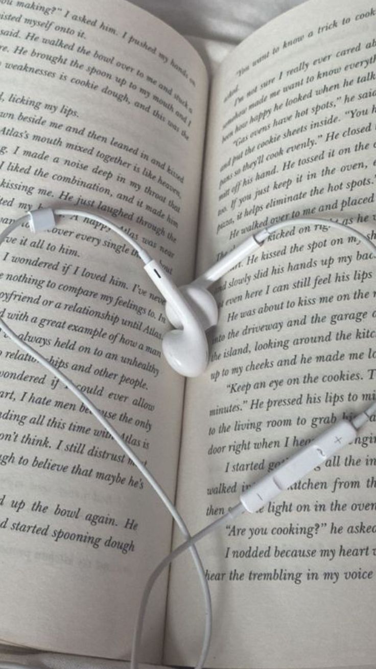 an open book with headphones laying on it's side in the shape of a heart